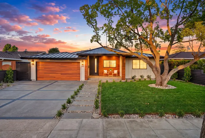 Single-story modern home with a wood garage door under a large shade tree at twilight, Los Gatos