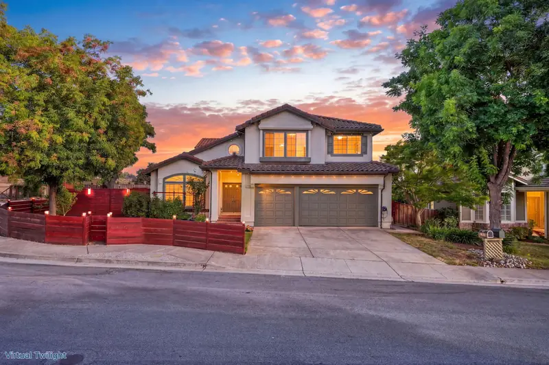 Two-story home with a tile roof behind a red fence at twilight, Morgan Hill