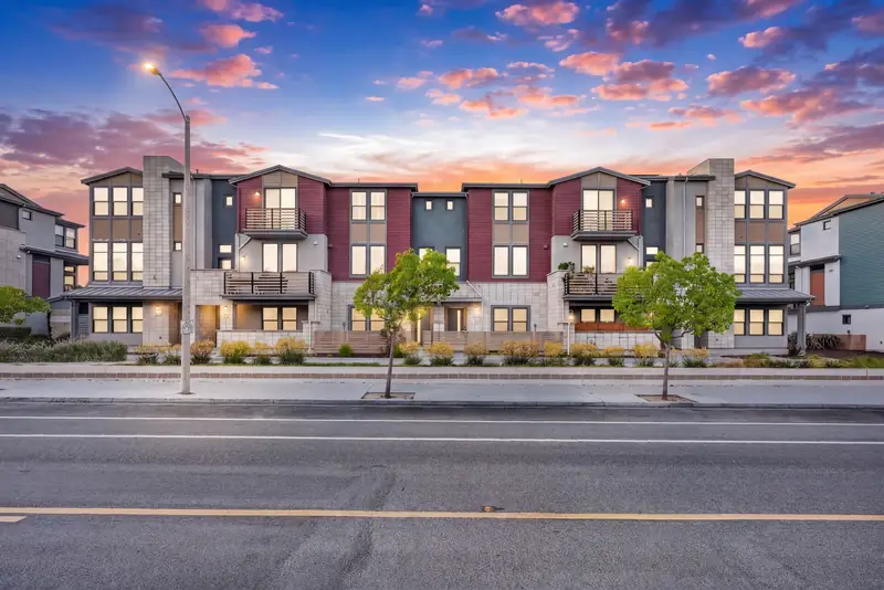 Row of three-story townhomes with lit windows at twilight, Sunnyvale