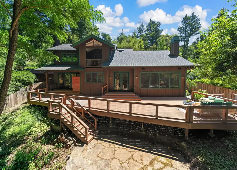 Back of a board and batten home with a wide deck among tall trees, Ben Lomond