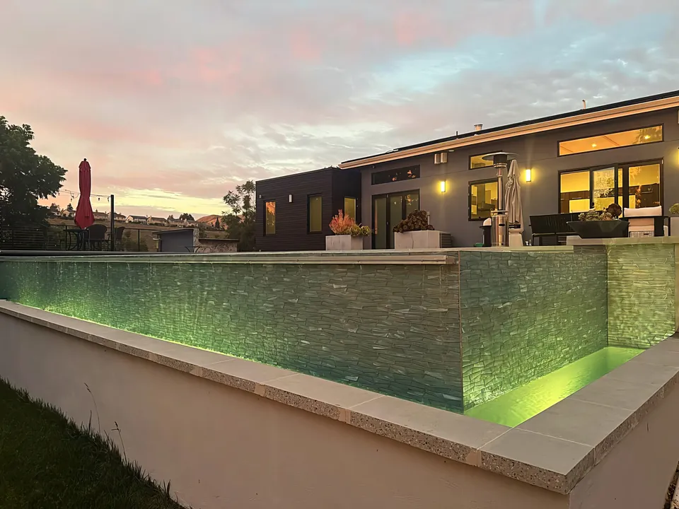 Raised vanishing edge: glass-tile wall lit at dusk