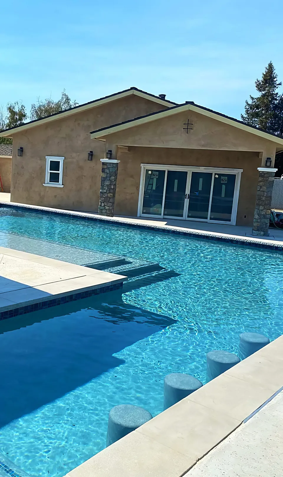 Bar seating: in-pool stools and a sun shelf in front of a pool house