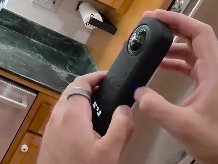 Both hands on the Theta Z1, its power light on the side