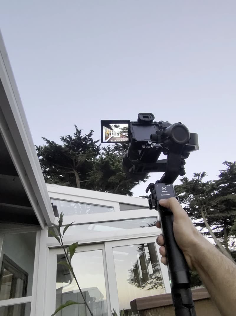 POV clip: gimbal held out over bushes at dusk to frame balcony doors
